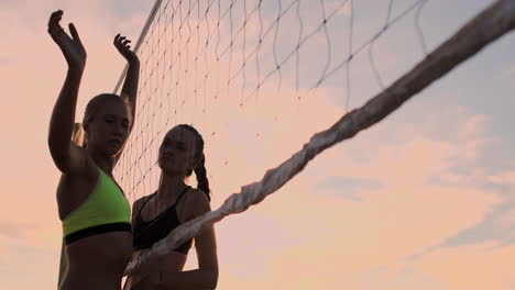 Sexy-Volleyballspielerinnen-Passen-Den-Ball-In-Der-Nähe-Des-Netzes-Hin-Und-Her-Und-Schlagen-Den-Ball-Bei-Sonnenuntergang-In-Zeitlupe.